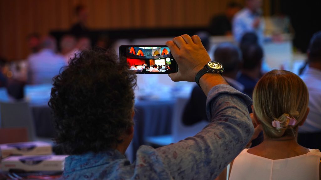 Event attendee taking a photo of a CEO presentation